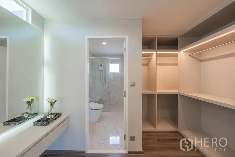 Detached House for rent in Samut Prakan - Walk-in closet with built-in shelves leading to an ensuite bathroom with glass shower.