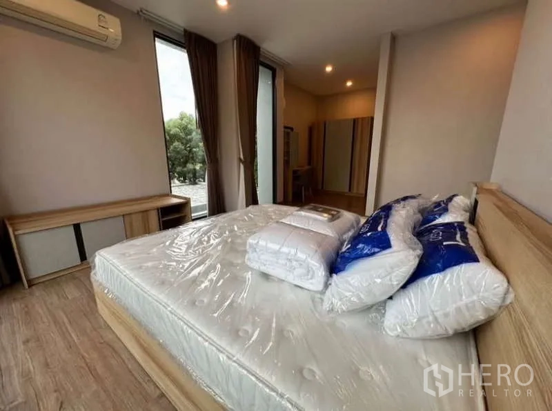 Townhouse for rent in Lat Phrao, Bangkok - Corner bedroom with new mattress, wide windows and green views.