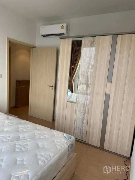 公寓 出租在Watthana, Bangkok - 卧室内木纹衣柜、床与分体空调。