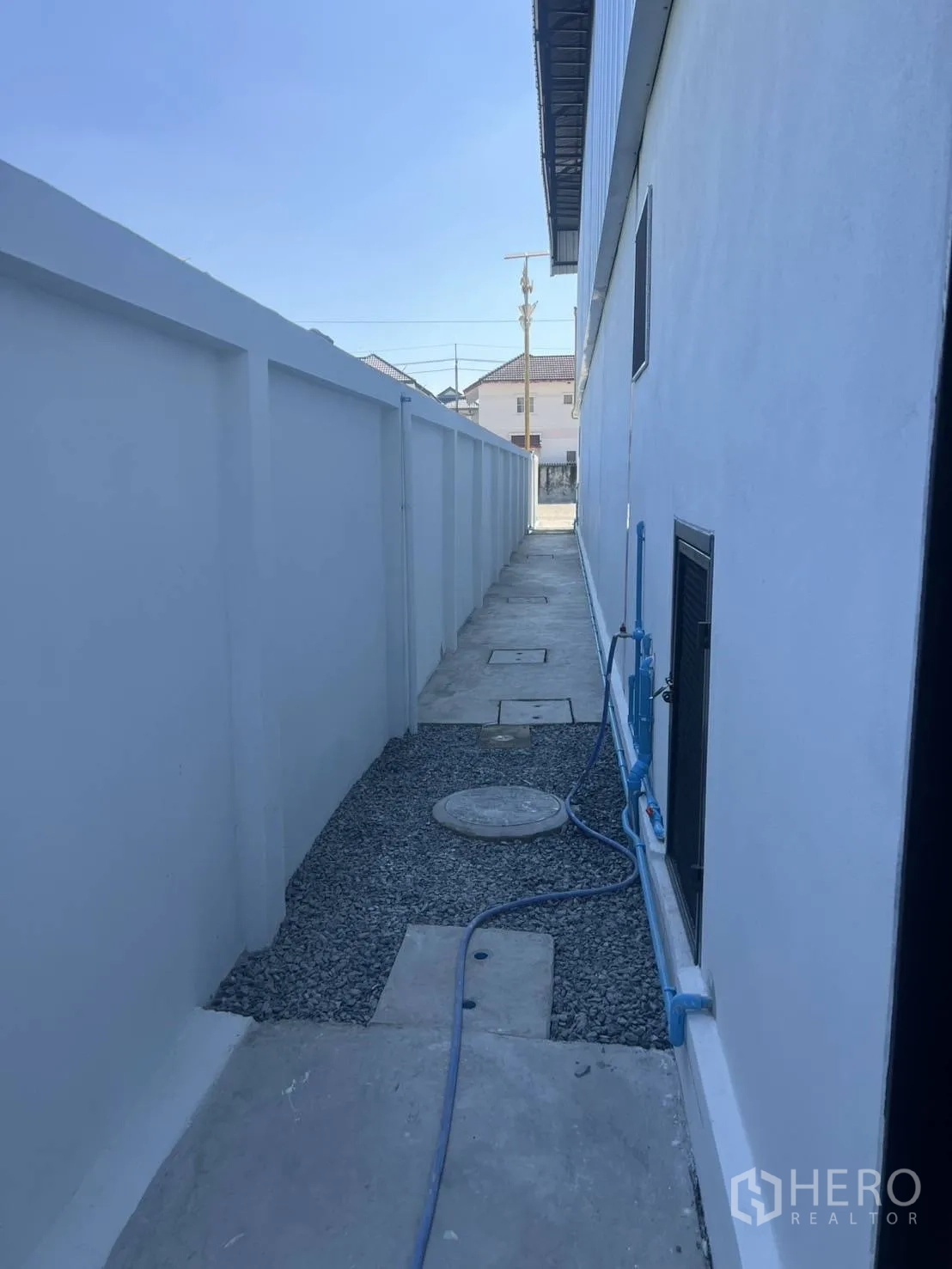 仓库 for rent in Bang Phli, Samut Prakan - 建筑外侧服务通道，设有管线与碎石地面。