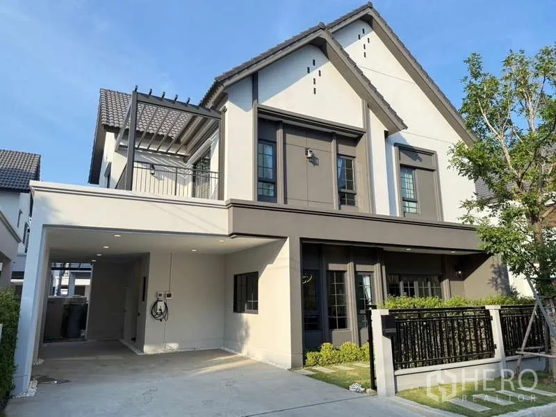 独立式住宅 出租在Bang Phli, Samut Prakan - 独栋住宅正立面，设阳台与有顶停车位。
