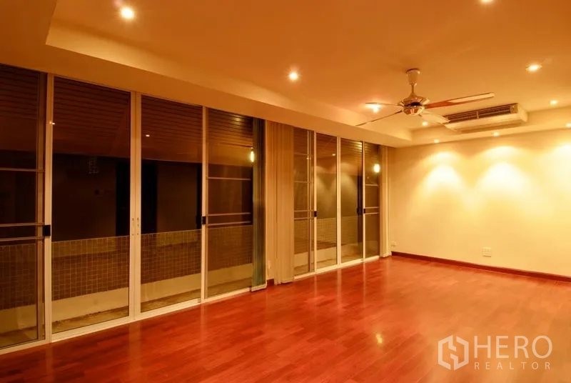 บ้าน ให้เช่าในWatthana, Bangkok - ห้องนั่งเล่นกว้าง พื้นไม้ ไฟดาวน์ไลท์ พัดลมเพดาน และประตูกระจกบานเลื่อน