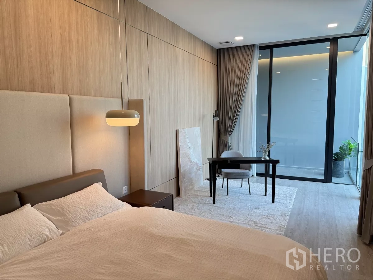Detached House for rent in Saphan Sung, Bangkok - Bedroom suite with wood panel wall, study desk and sliding glass door to a balcony.