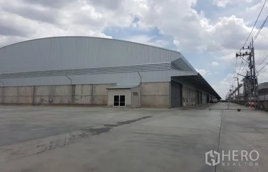 Warehouse for rent in Lam Luk Ka, Pathum Thani - Corner view of a large industrial warehouse block with a wide concrete yard.