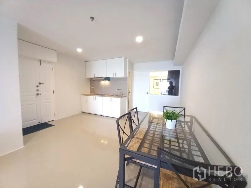 Condominium for rent in Khlong Toei, Bangkok - Entry area with white kitchenette and dining table under recessed lights.
