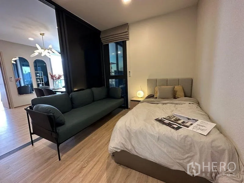คอนโด ให้เช่าในRatchathewi, Bangkok - ห้องนอนรองพร้อมเตียงเดี่ยว โซฟา และฉากกั้นกระจกเลื่อนไปยังโซนรับแขก