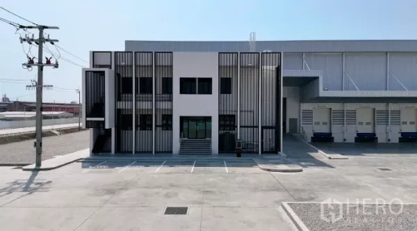 工厂 出租在Samut Prakan - 办公楼正立面，玻璃入口与金属遮阳格栅，旁接装卸月台和停车区