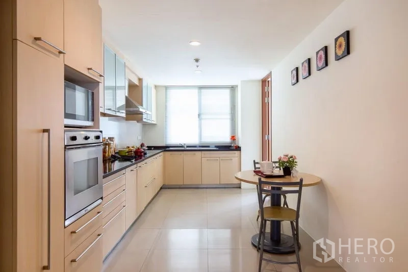 Condominium for rent in Bang Rak, Bangkok - Enclosed kitchen with built-in oven, ample cabinetry, black countertops and a breakfast nook.