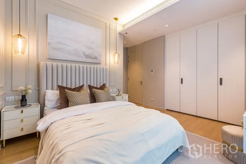 Condominium for rent in Pathum Wan, Bangkok - Second bedroom with built-in wardrobes, pendant lights, and a plush bed.