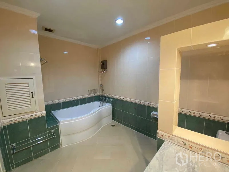 Townhouse for rent or sale in Mueang Samut Prakan, Samut Prakan - Bathroom featuring a corner bathtub with green and beige tiles.