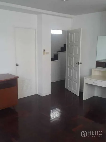 Detached House for rent in Watthana, Bangkok - Compact room with dark wood floors, white doors, and staircase access.