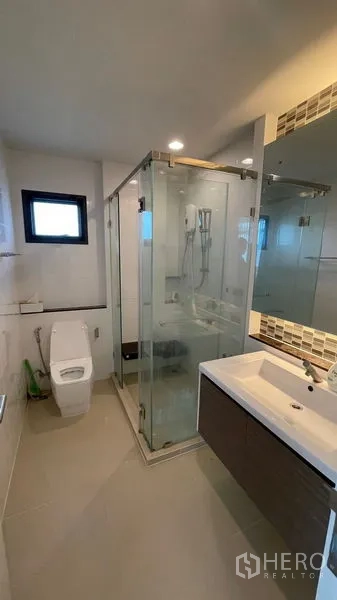 Detached House for rent in Bang Kapi, Bangkok - Bathroom featuring glass-enclosed shower, vanity, toilet and small window.