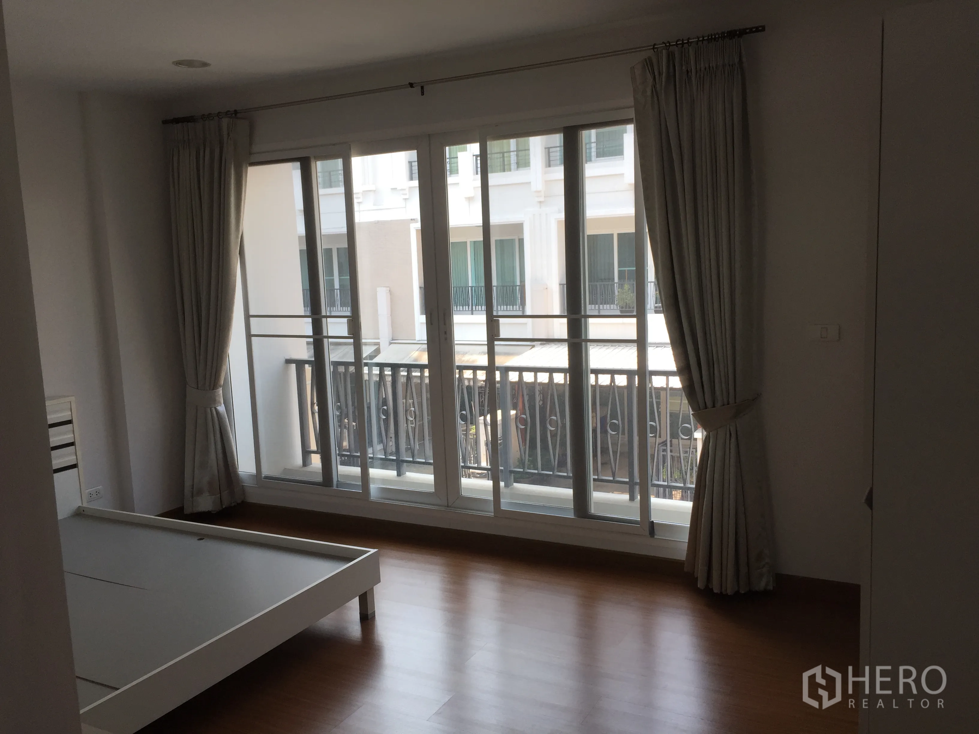 Townhouse for rent in Bang Kho Laem, Bangkok - Spacious bedroom with wood floors, large sliding glass doors and a balcony railing.