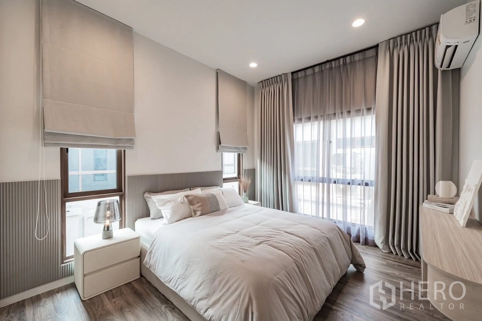 Detached House for sale in Bang Kapi, Bangkok - Cozy secondary bedroom with queen bed, soft grey drapes, wood flooring and bedside tables, offering calm comfort.