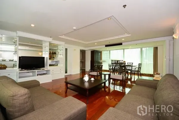 Apartment for rent in Khlong Toei, Bangkok - Spacious lounge with built-in TV cabinet, sofa set and adjoining dining area on glossy wood floors.