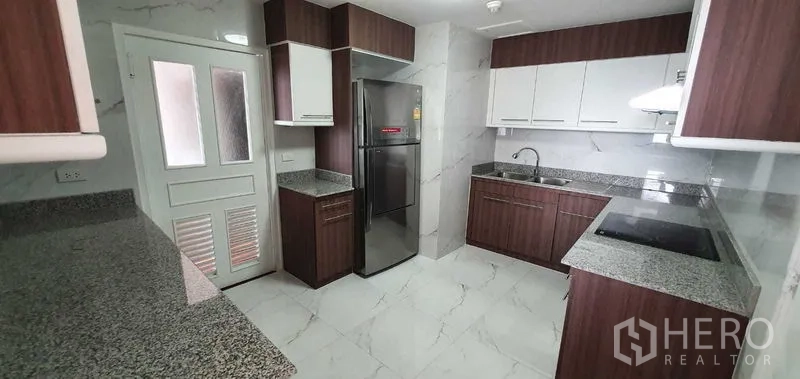 公寓 出租在Khlong Toei, Bangkok - 现代U型厨房，花岗岩台面，白色与木色橱柜，配冰箱。