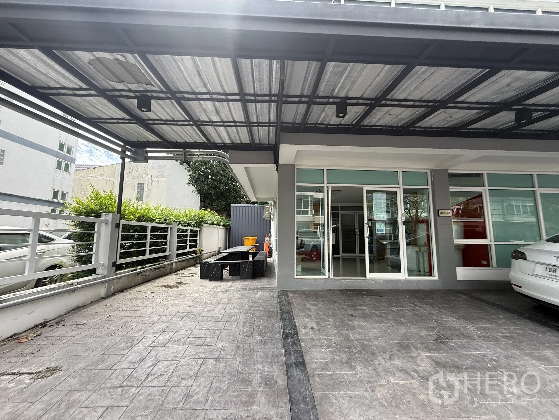 办公空间 出租在Bueng Kum, Bangkok - 金属雨棚入口，玻璃门与侧边步道及长椅。