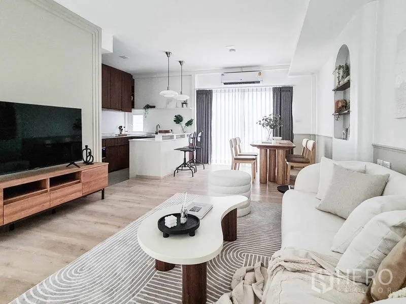 联排别墅 出租在Prawet, Bangkok - 一体化客餐厨空间，中岛、圆餐桌与大尺寸电视柜。