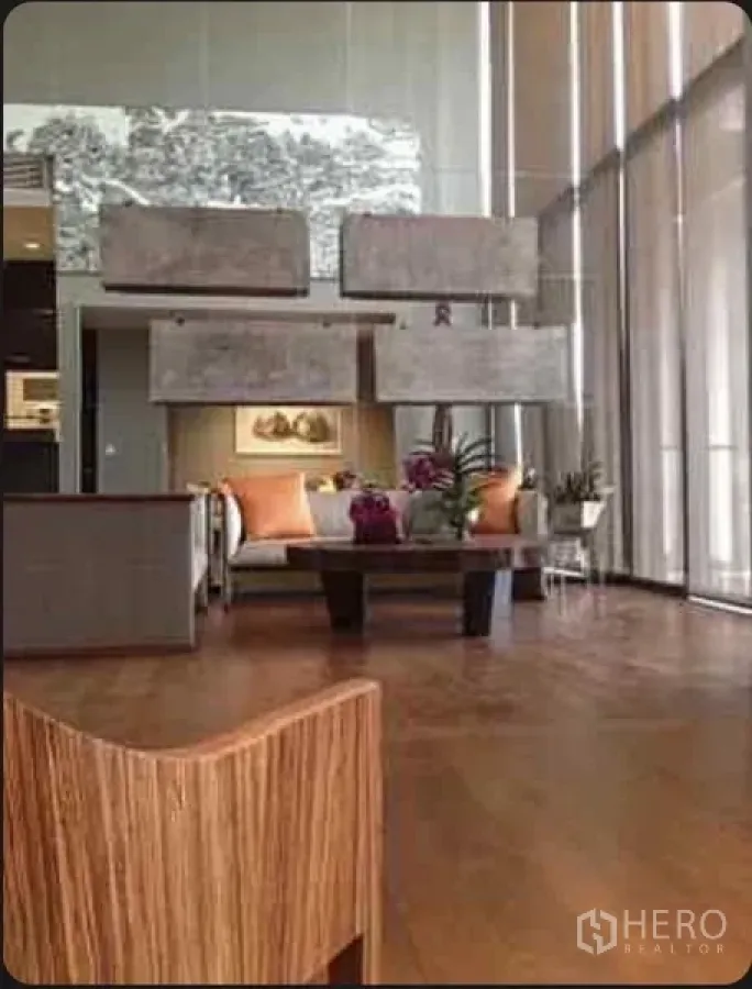 Condominium for rent in Sathon, Bangkok - Elegant double-height lounge with sofa seating, coffee table and tall glass windows.
