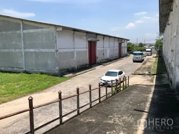 工厂 出租在Lat Krabang, Bangkok - 仓库区内部道路，两侧建筑之间可见卡车与轿车。