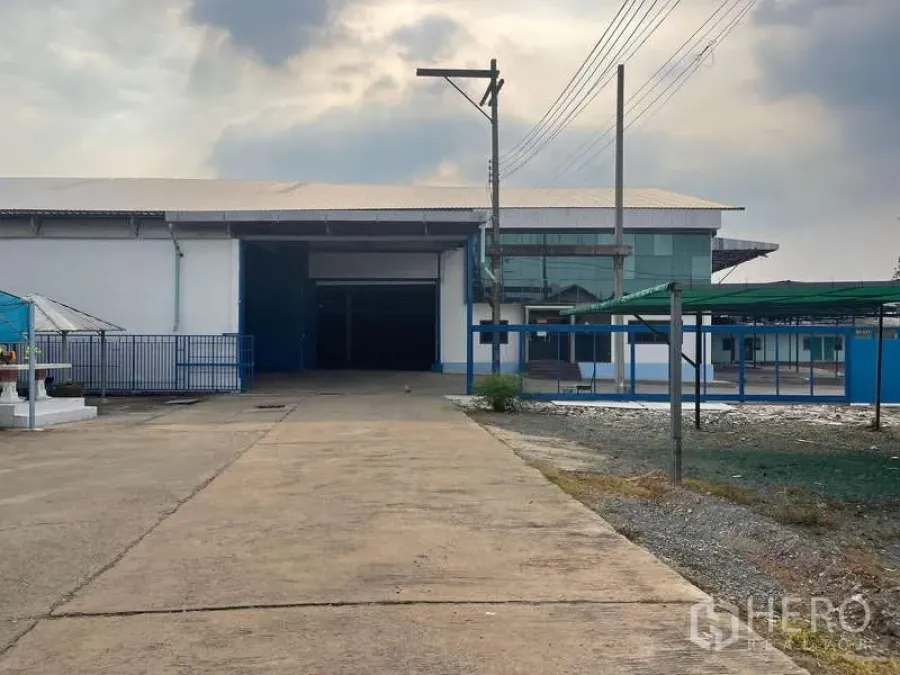Warehouse for rent in Nong Khaem, Bangkok - Driveway approach to the warehouse complex with glass office facade and gates.