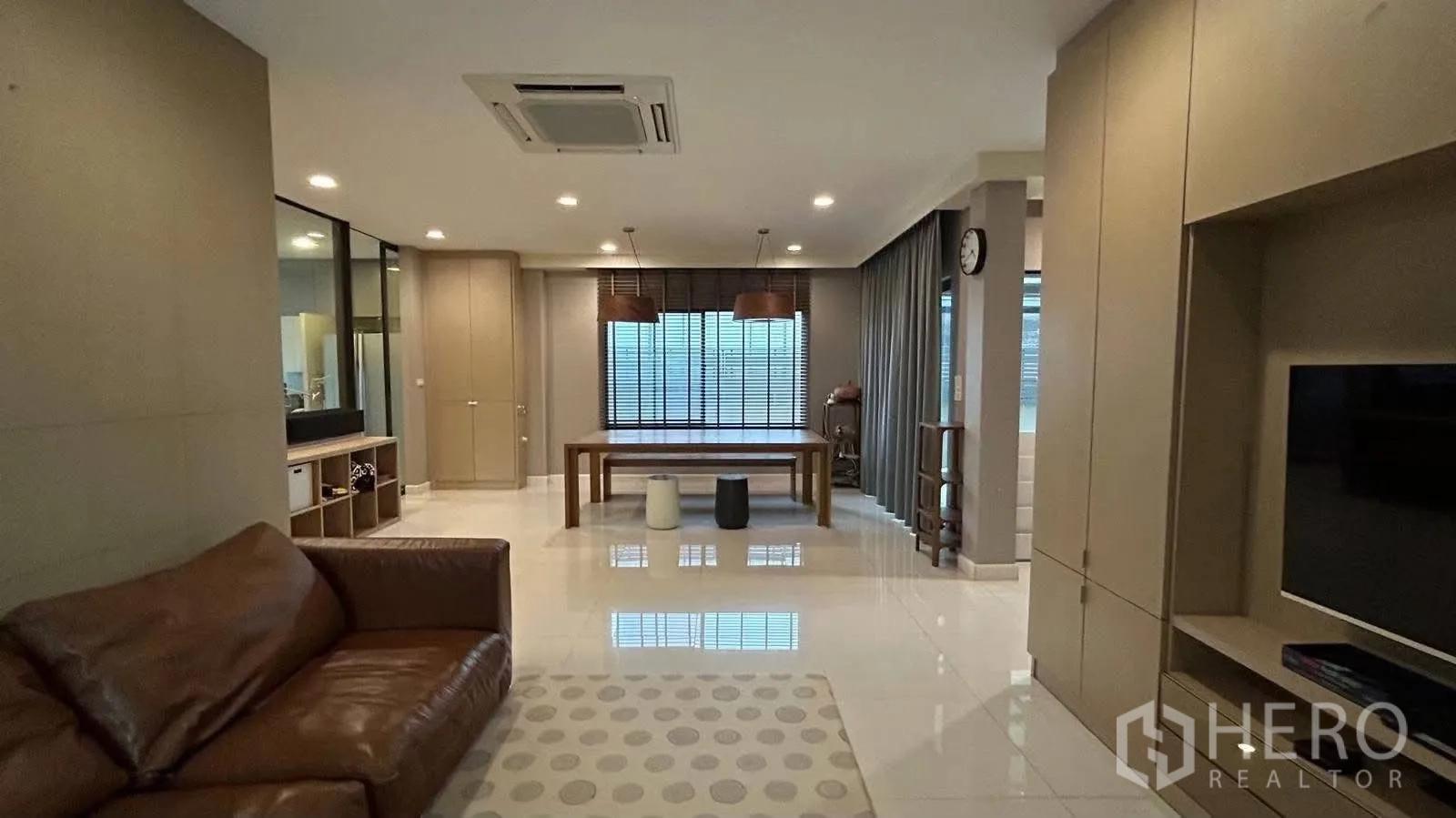 Detached House for rent in Prawet, Bangkok - View across living area toward dining table, window blinds, and a ceiling cassette air-conditioner.