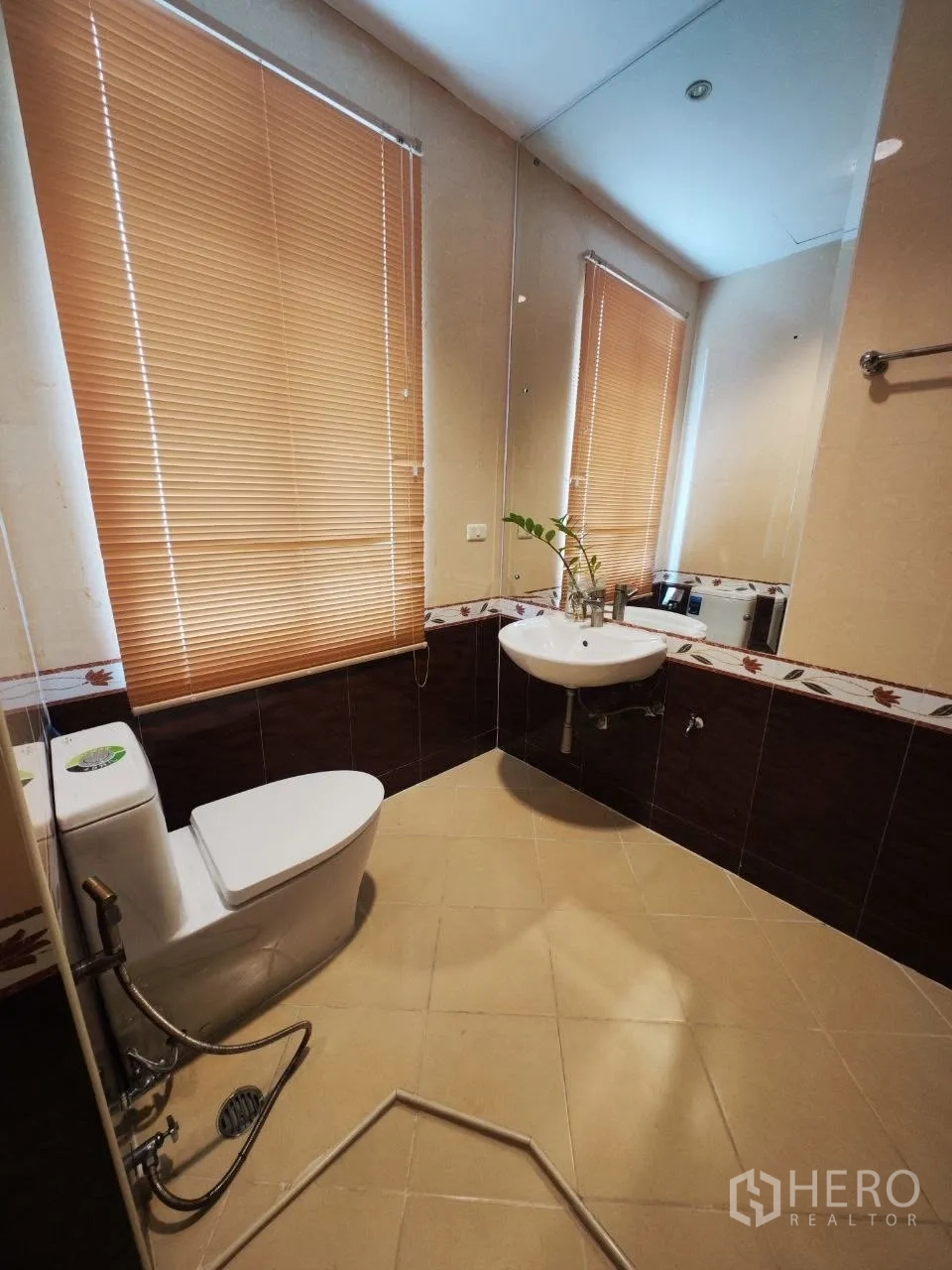 Home Office for rent in Bang Na, Bangkok - Bathroom with large mirror, blinds, toilet and wall-mounted sink.