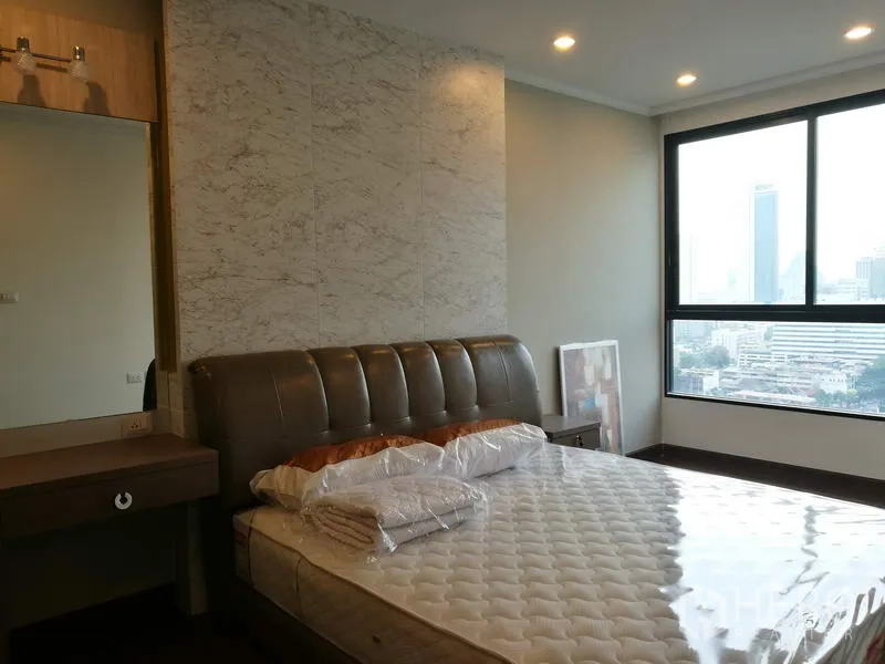 Condominium for rent in Sathon, Bangkok - Bright bedroom with upholstered bed, marble accent wall and large window offering a city view in a Sathon condo.