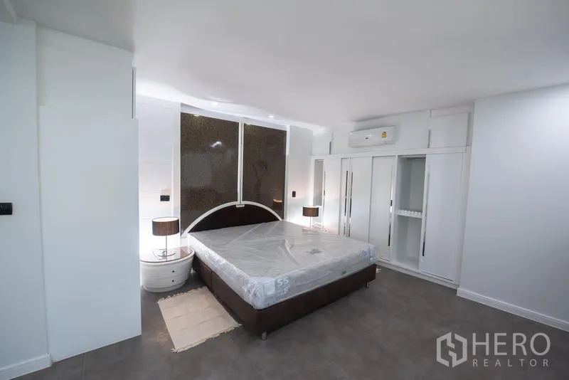 Condominium for rent in Khlong Toei, Bangkok - Master bedroom with king bed, built-in wardrobes, nightstands and feature wall.