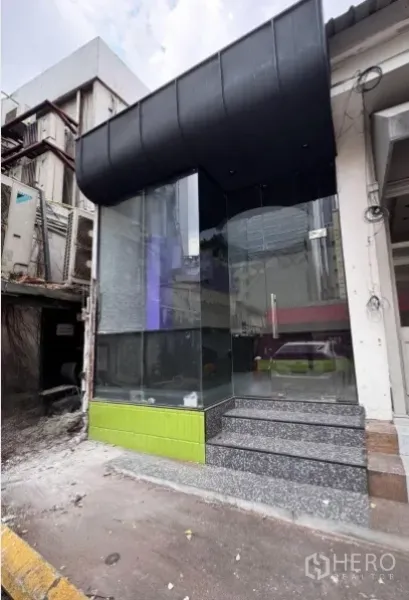 Retail Space for rent in Watthana, Bangkok - Street-facing corner retail frontage with full-height glass, black awning, and terrazzo steps.