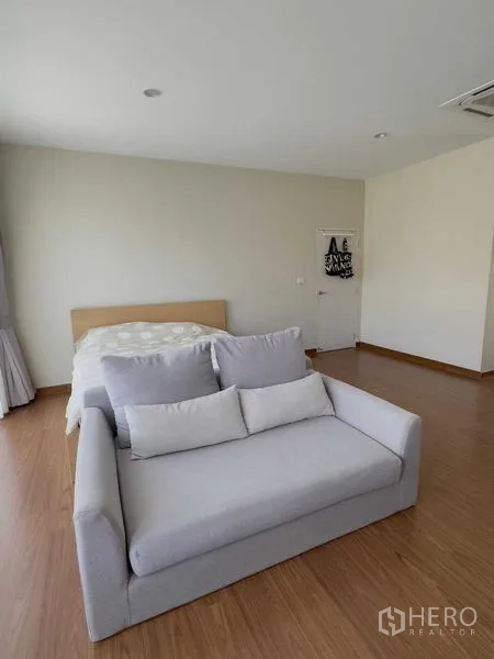 บ้าน ให้เช่าหรือขายในBang Khen, Bangkok - มุมมองห้องนอนมาสเตอร์มีโซฟาสีเท้าที่ปลายเตียง พื้นลายไม้