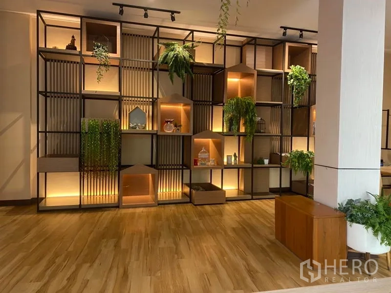 Retail Space for rent in Khlong Toei, Bangkok - Feature wall of illuminated modular shelving with plants and decor in a wood-floored retail area.