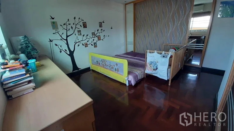 คอนโด ให้เช่าในWatthana, Bangkok - ห้องนอนอบอุ่น มีเตียงเด็ก ผนังลายต้นไม้ พื้นไม้ และตู้บิลท์อินข้างหน้าต่าง