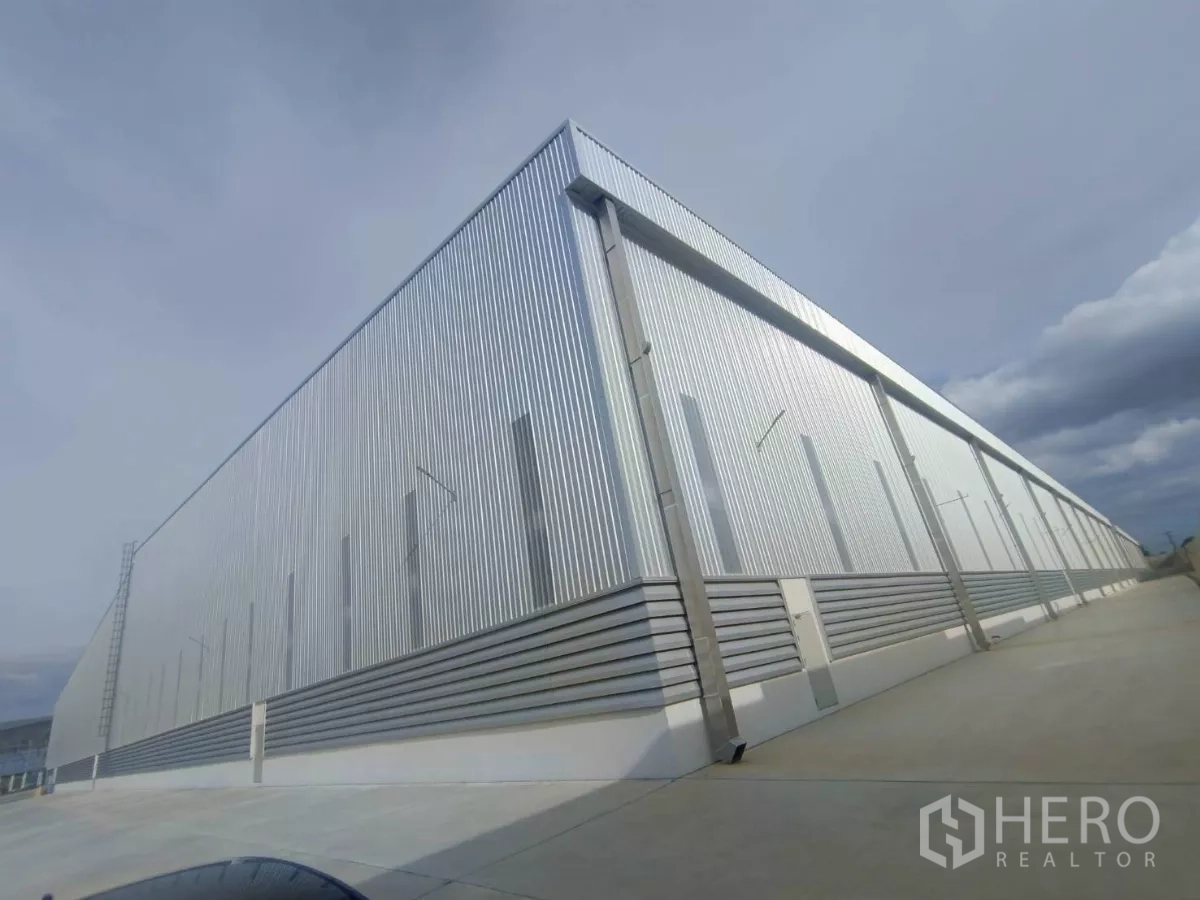 工厂 出租在Si Racha, Chon Buri - 金属板外墙的建筑后立面，配整洁的混凝土通道。