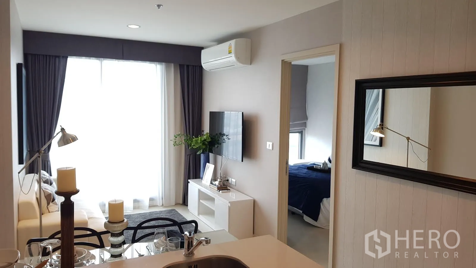 公寓 出租在Khlong Toei, Bangkok - 开放式起居与用餐区，沙发、电视墙与明亮落地窗。