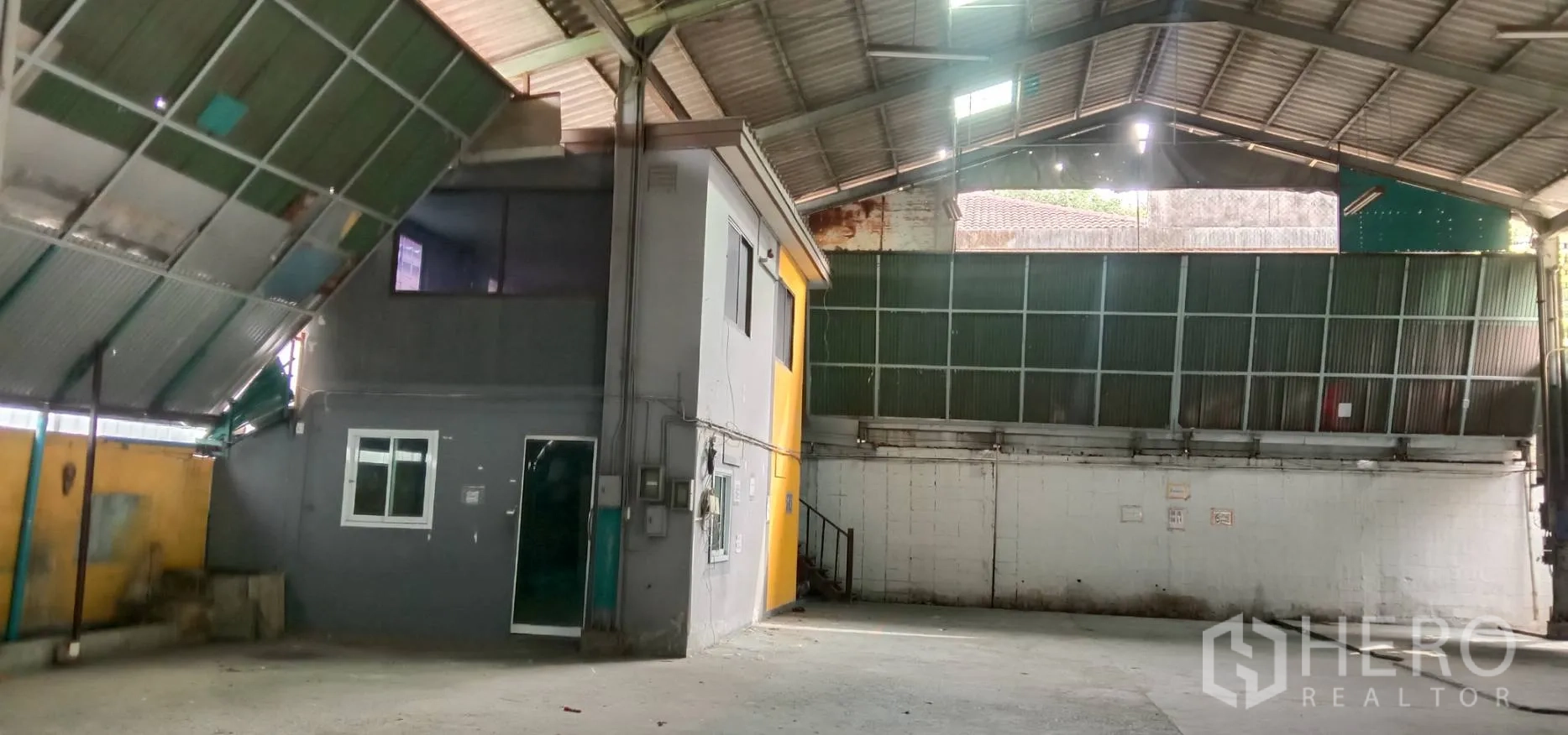 Warehouse for rent in Bueng Kum, Bangkok - Wide interior bay with ventilated metal wall panels, roller shutter entry and clear open floor ideal for storage or loading.