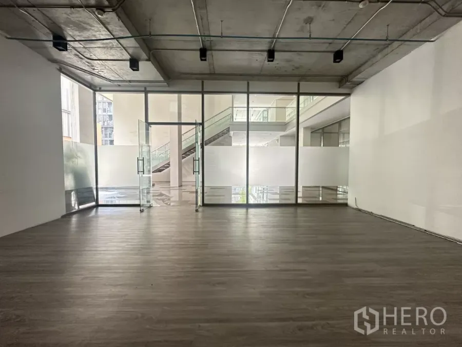 Retail Space for rent - Open-plan retail unit with floor-to-ceiling glass frontage, frosted panels, wood-look flooring and an exposed ceiling.