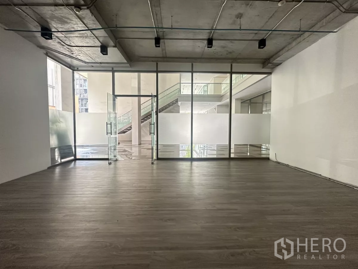 Retail Space for rent - Open-plan retail unit with floor-to-ceiling glass frontage, frosted panels, wood-look flooring and an exposed ceiling.