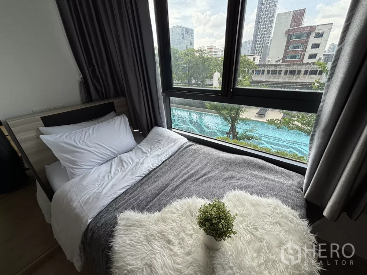 公寓 出租在Phra Khanong, Bangkok - 转角床靠落地窗，可欣赏泳池全景。