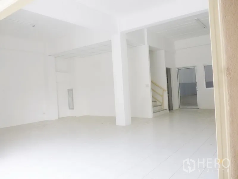 Factory for rent or sale in Pathum Thani - Bright office area with white tiled floor, staircase to mezzanine and a glass door connecting to the warehouse.