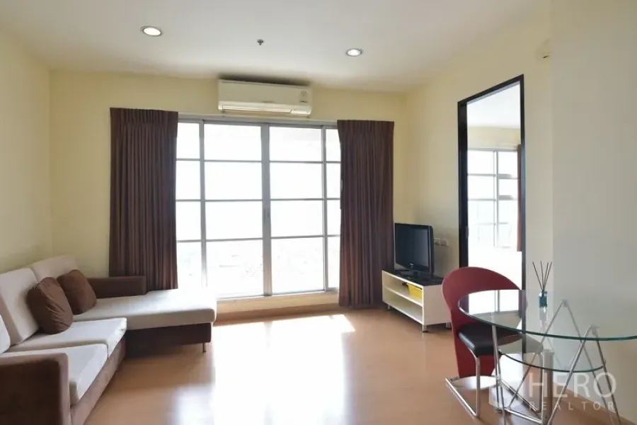 公寓 出租在Ratchathewi, Bangkok - 明亮客厅，转角沙发与电视柜，大幅推拉玻璃门引入自然采光。