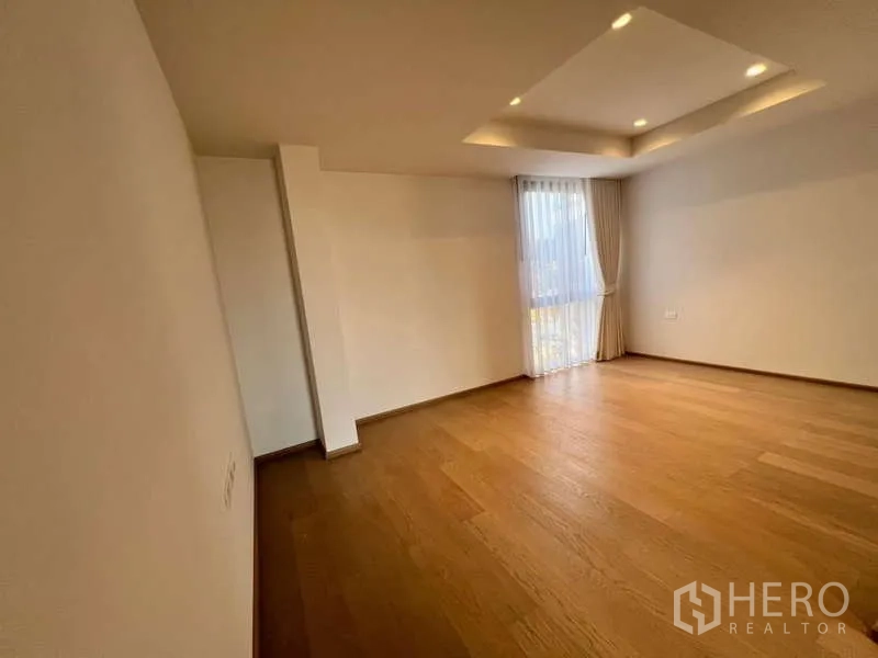 Townhouse for rent in Phra Khanong, Bangkok - Large secondary bedroom with recessed ceiling lights and wood flooring.