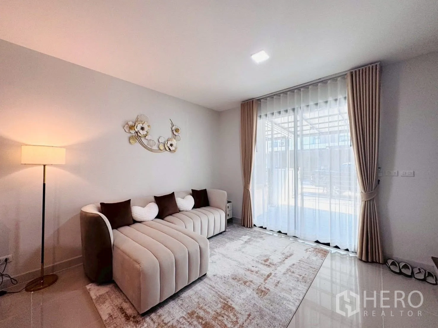 Townhouse for rent in Bang Phli, Samut Prakan - Bright living room with plush beige sofa, floor-to-ceiling sliding glass doors and sheer curtains in a Bang Phli townhouse.