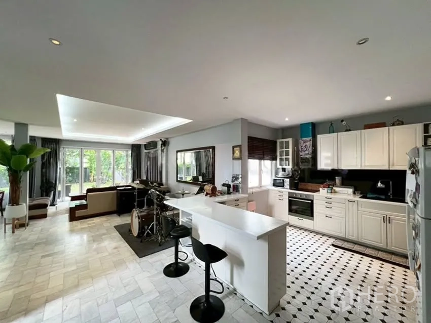 Detached House for rent in Phra Khanong, Bangkok - Open-plan kitchen with white cabinets, island, and adjoining living space.