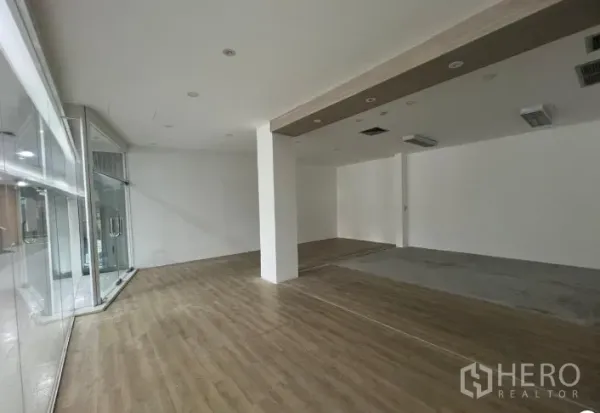 Retail Space for rent - Angle view of retail space with wood-look floors, recessed lighting and a corner glass display wall.