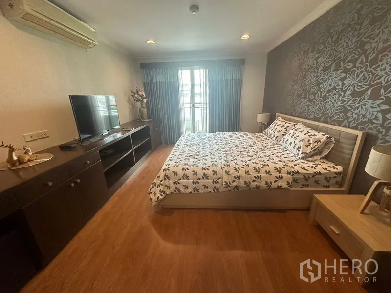 คอนโด ให้เช่าในWatthana, Bangkok - ห้องนอนใหญ่ เตียงคิง วอลเปเปอร์ลายดอก ตู้ทีวี และทางออกสู่ระเบียง
