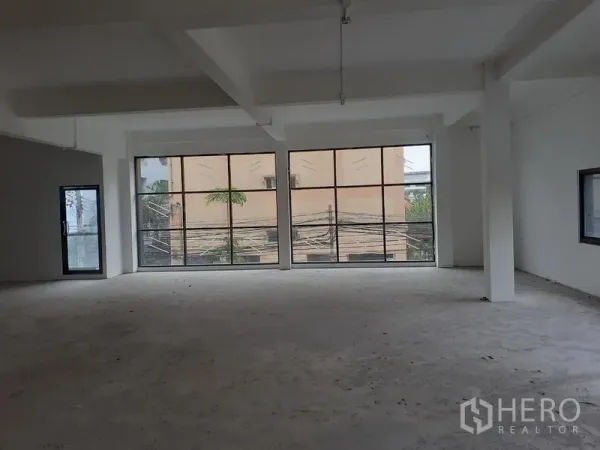 Office Space for rent in Khlong Toei, Bangkok - Bright shell‑and‑core office with two full‑height grid windows and a side glass door.