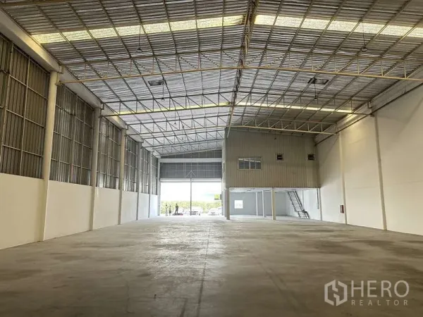 Factory for rent in Khlong Luang, Pathum Thani - Wide warehouse bay facing large shutter doors and an elevated office block.
