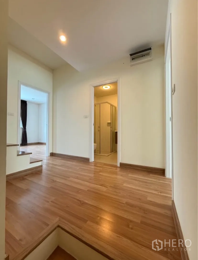 Townhouse for rent in Suan Luang, Bangkok - Upper-floor landing leading to bedrooms and bathroom with wood flooring.