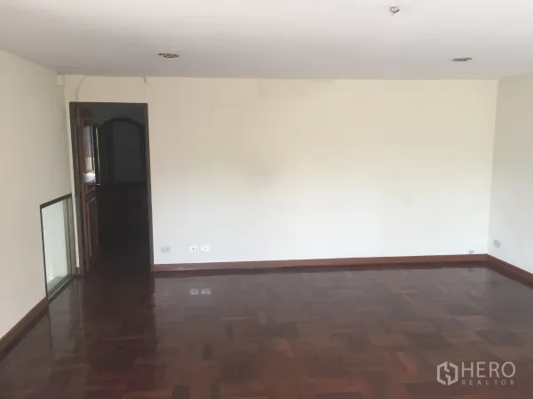 带办公室的家 出售在Watthana, Bangkok - 空房间，深色拼花木地板与白墙，木门入口。